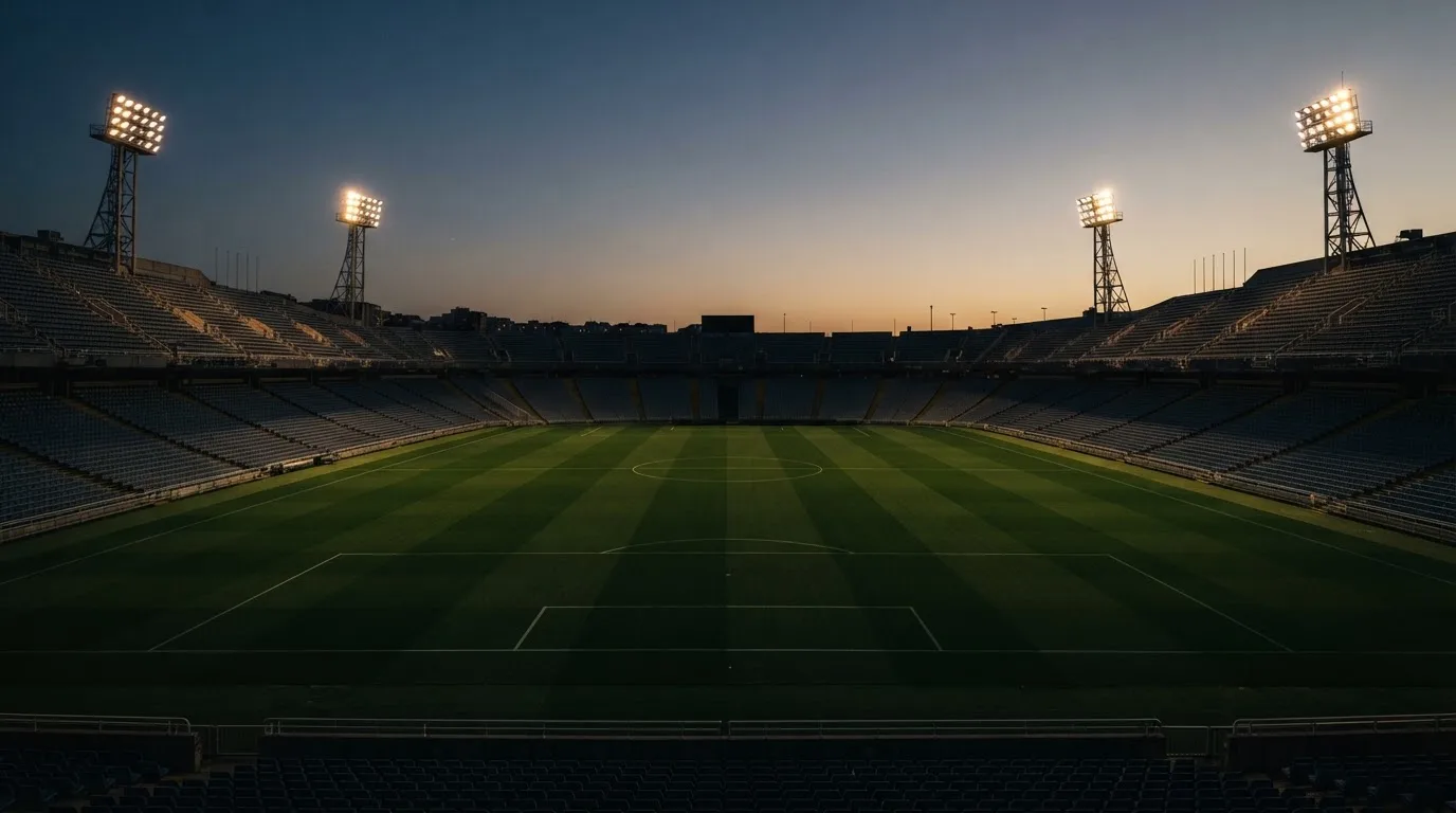 Een leeg voetbalstadion met lichtmasten bij schemering