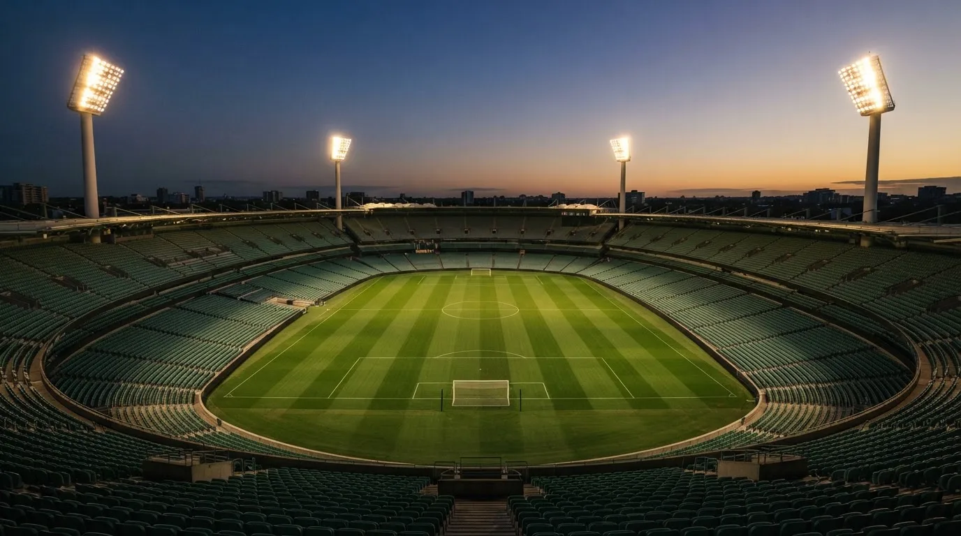 Een leeg voetbalstadion met lichtmasten bij schemering