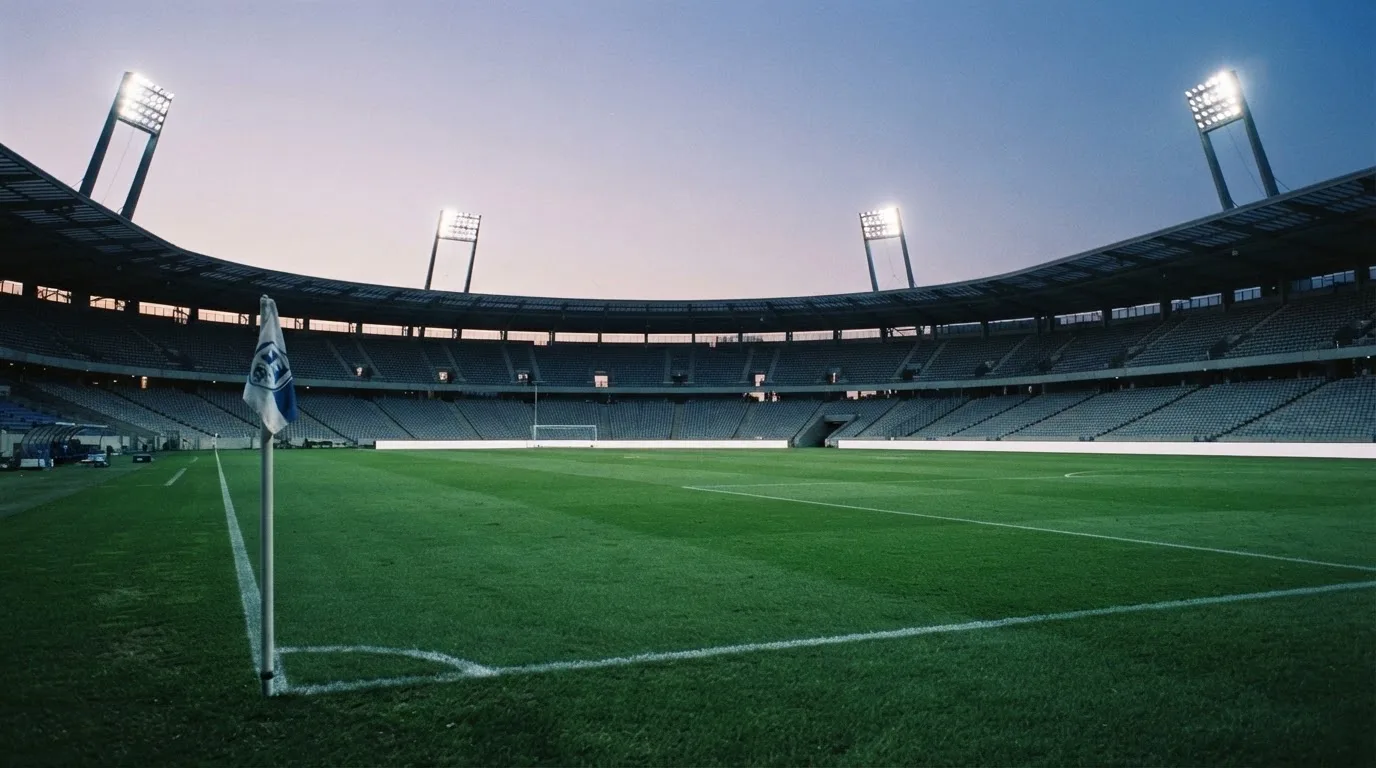 Een leeg voetbalstadion met lichtmasten bij schemering