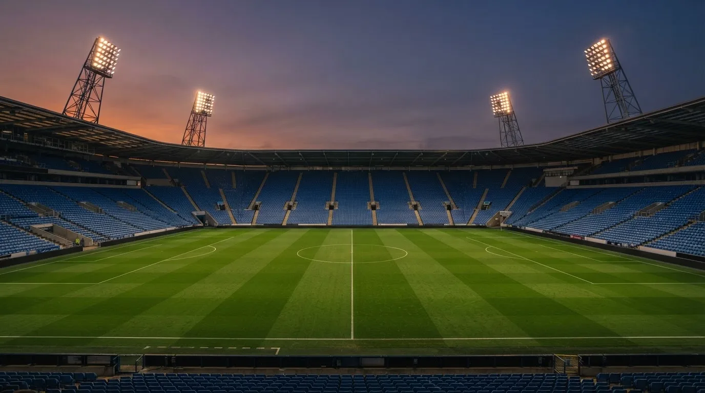 Een leeg voetbalstadion met lichtmasten bij schemering