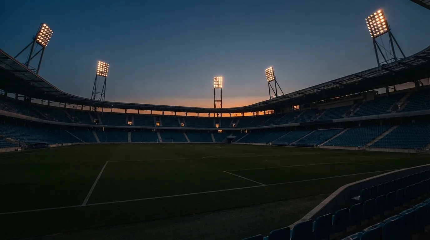 Een leeg voetbalstadion met lichtmasten bij schemering