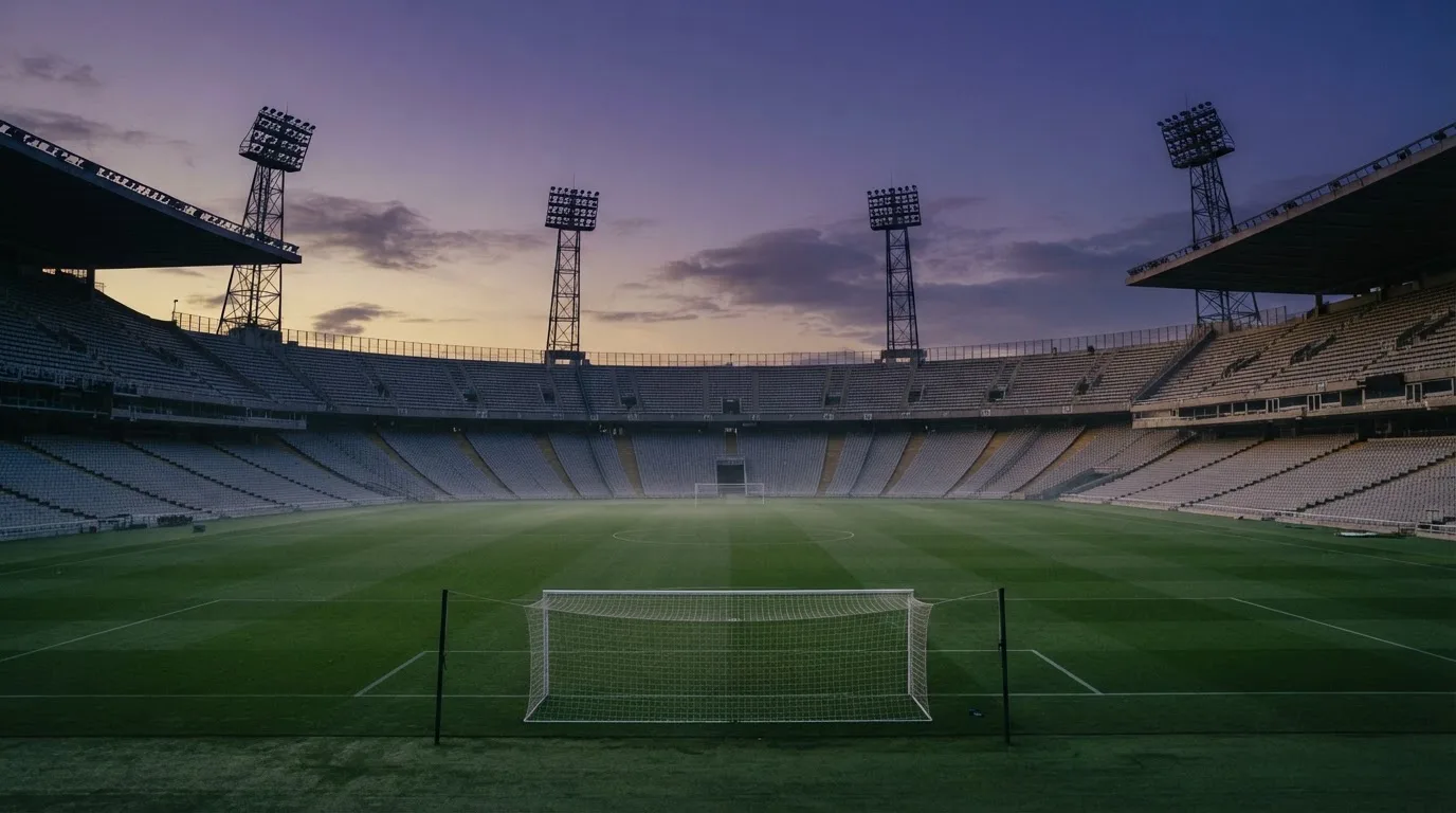 Een leeg voetbalstadion met lichtmasten bij schemering