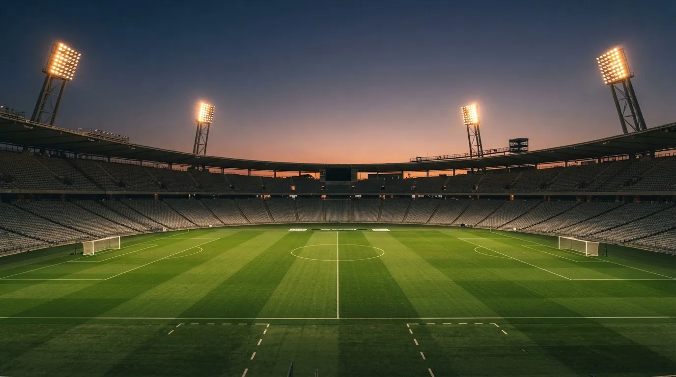 Een leeg voetbalstadion met lichtmasten bij schemering