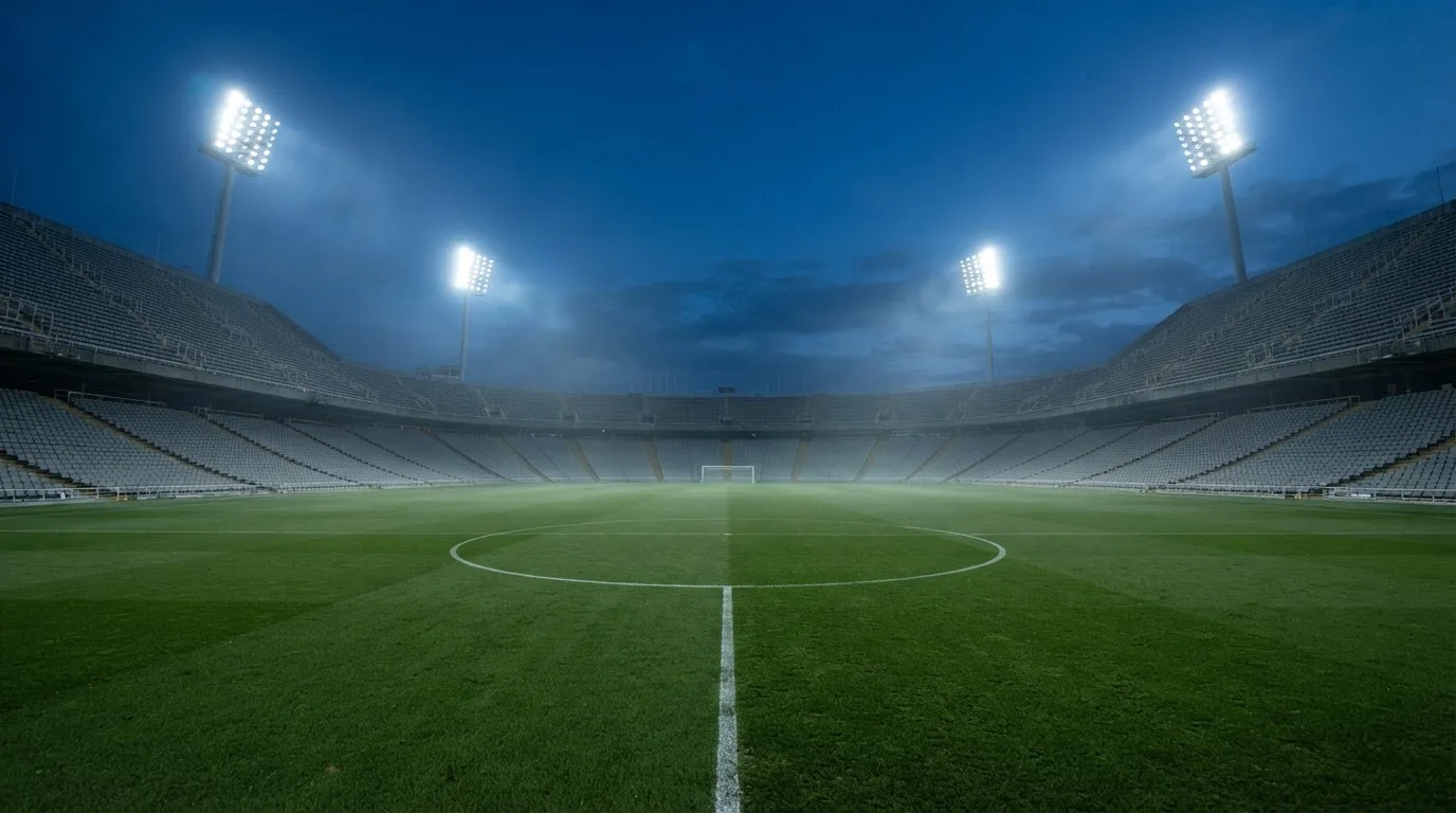 Een leeg voetbalstadion met lichtmasten bij schemering