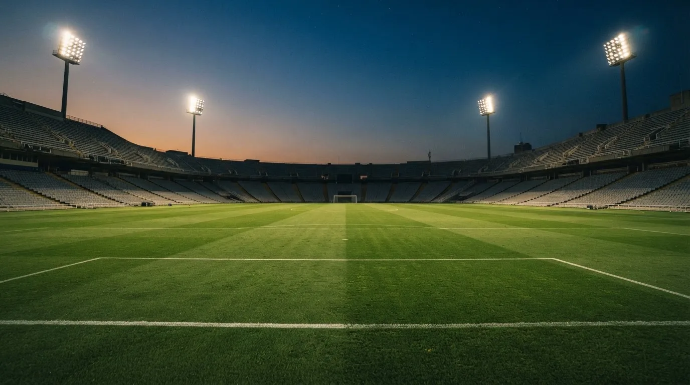 Een leeg voetbalstadion met lichtmasten bij schemering