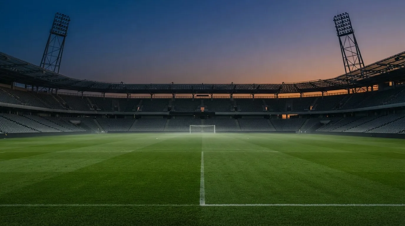 Een leeg voetbalstadion met lichtmasten bij schemering