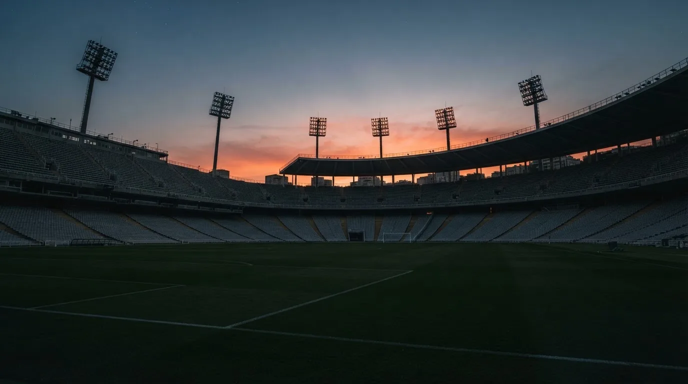 Een leeg voetbalstadion met lichtmasten bij schemering
