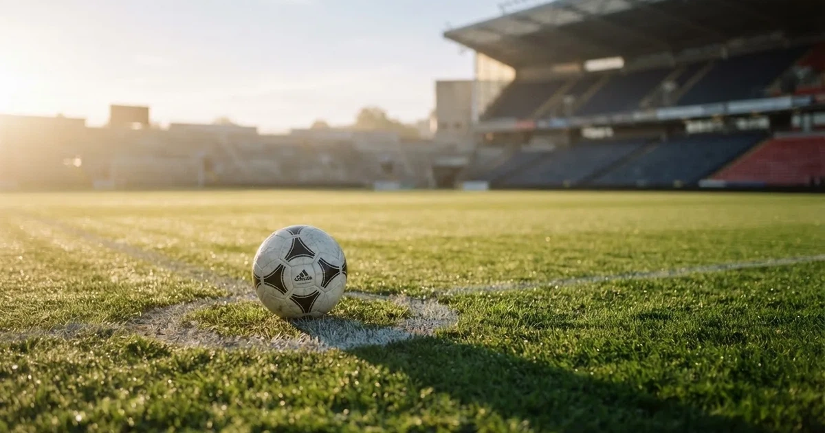 Een voetbal op de middenstip van een grasveld in het ochtendlicht