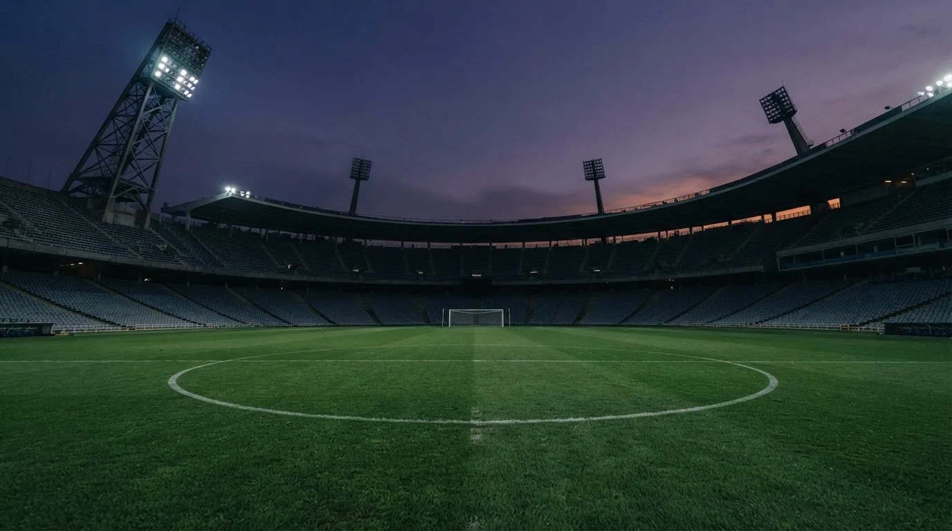 Een leeg voetbalstadion met lichtmasten bij schemering