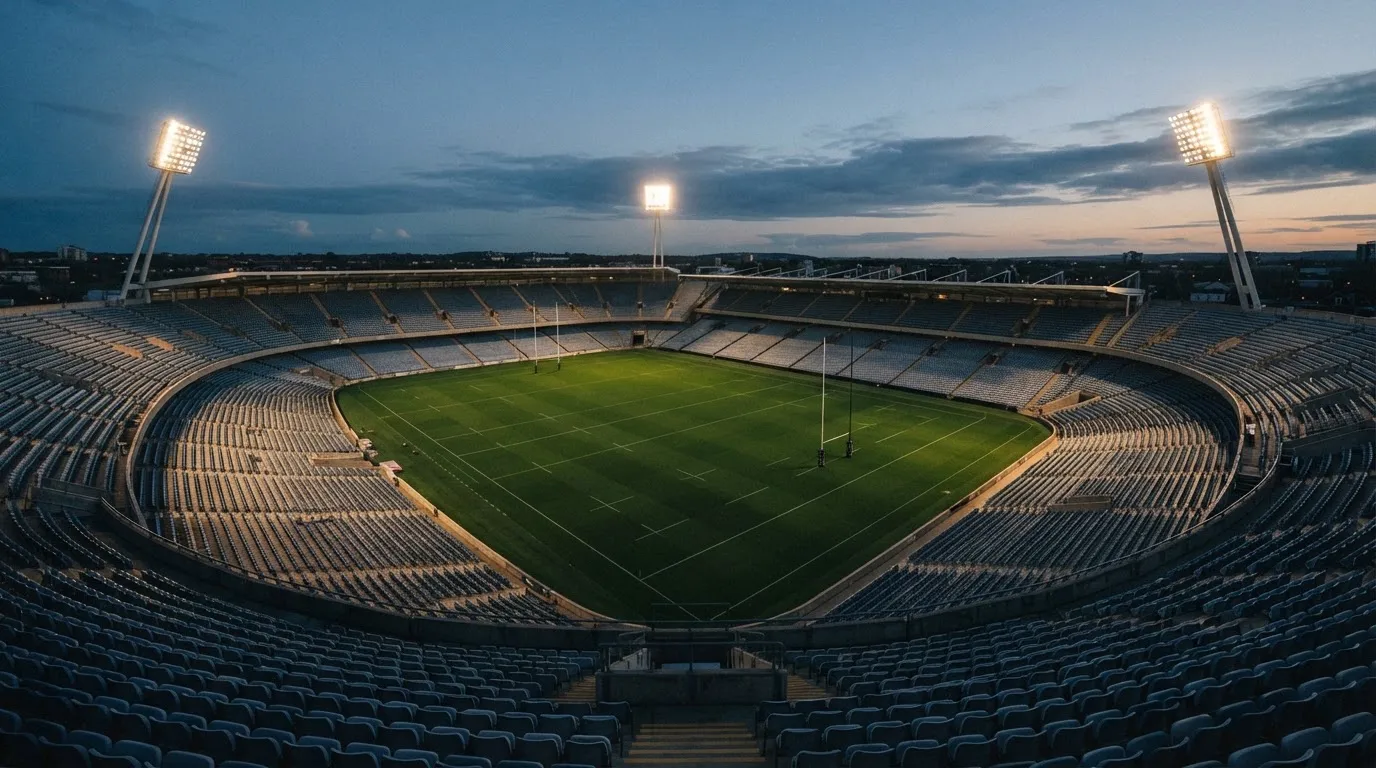 Een leeg voetbalstadion met lichtmasten bij schemering