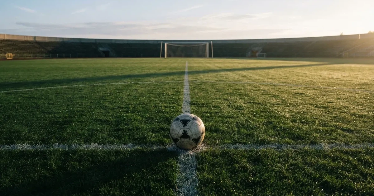 Een voetbal op de middenstip van een grasveld in het ochtendlicht