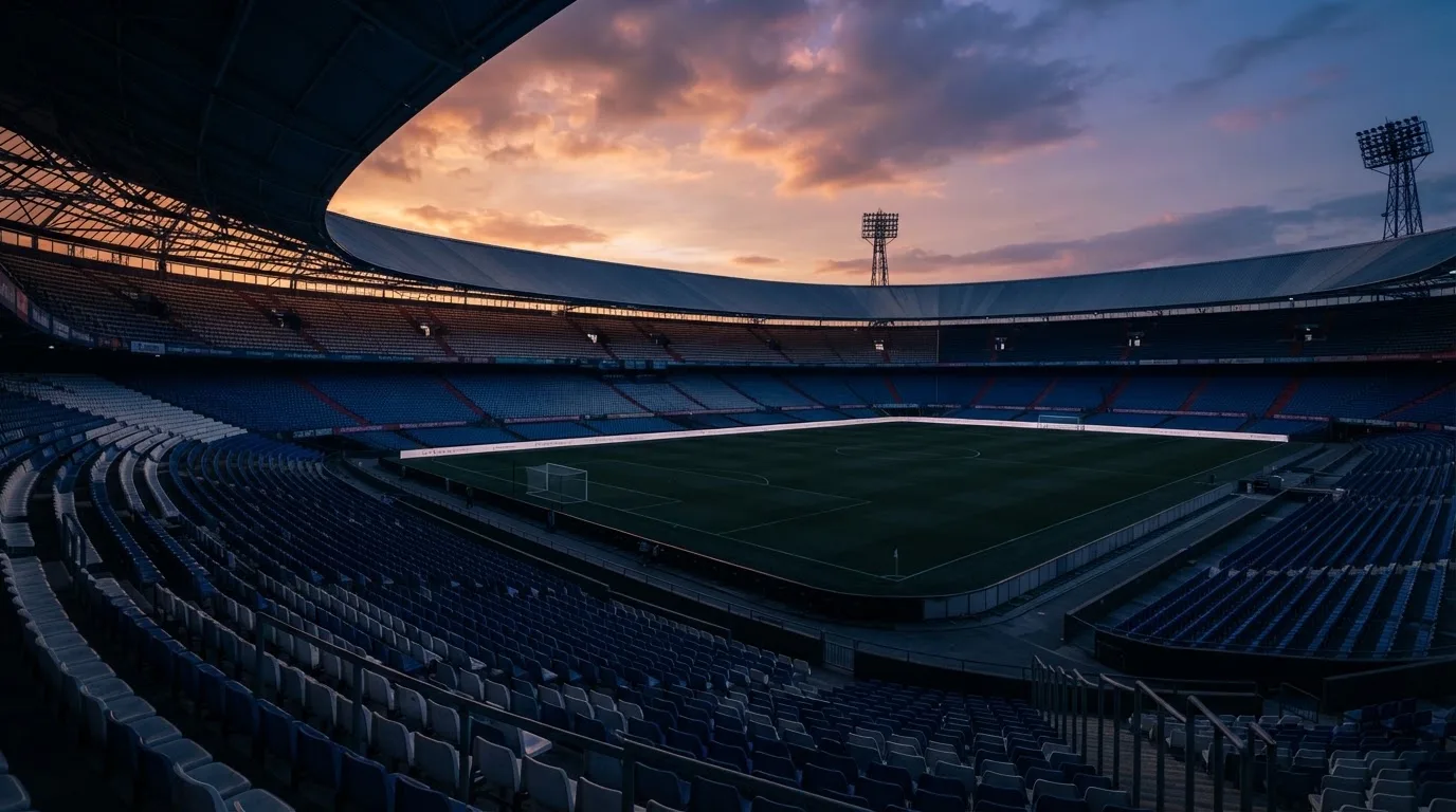 Een leeg voetbalstadion met lichtmasten bij schemering