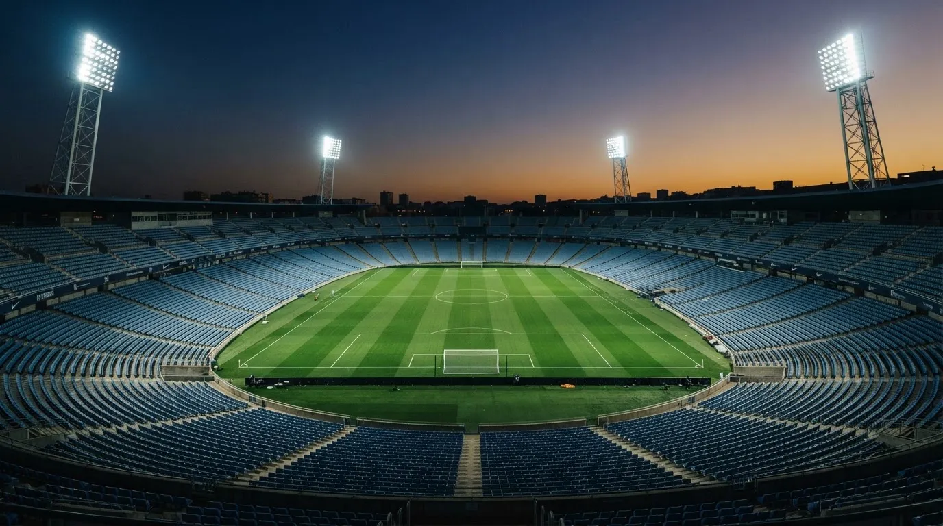 Een leeg voetbalstadion met lichtmasten bij schemering