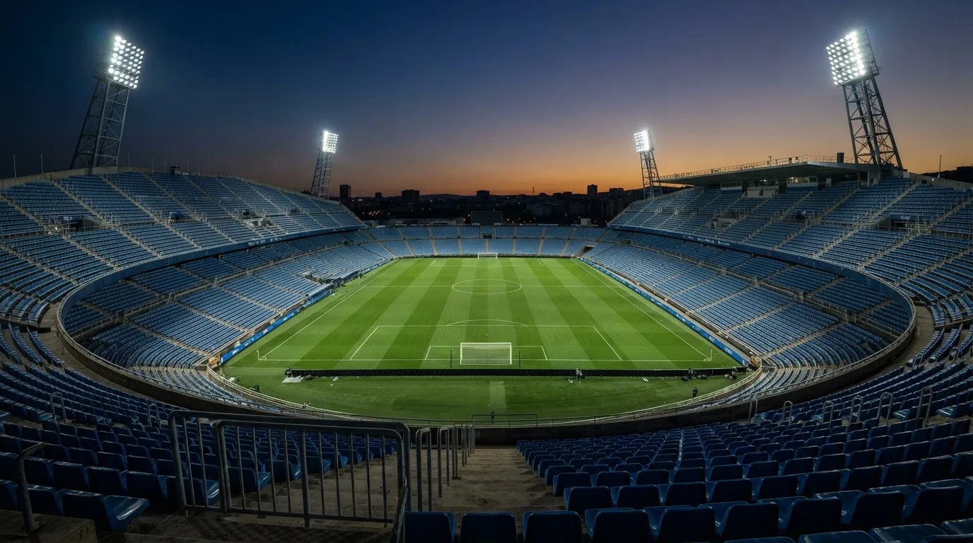 Een leeg voetbalstadion met lichtmasten bij schemering
